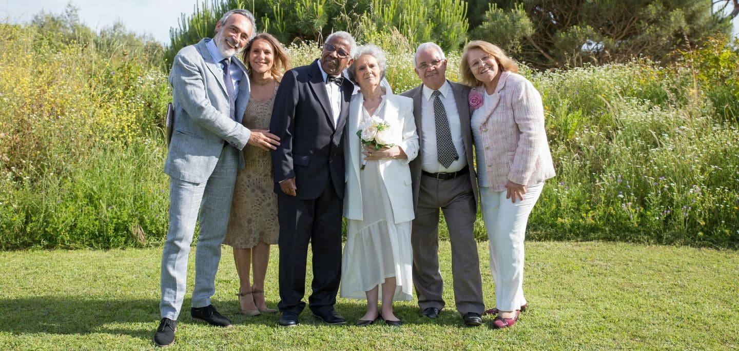 Cette image présente un couple de mariés âgés, accompagnés de convives