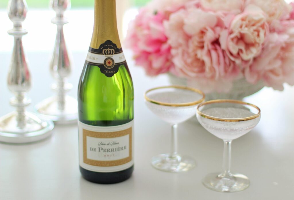Bouteille de champagne et coupes dorées avec bouquet de pivoines roses pour un vin d'honneur de mariage